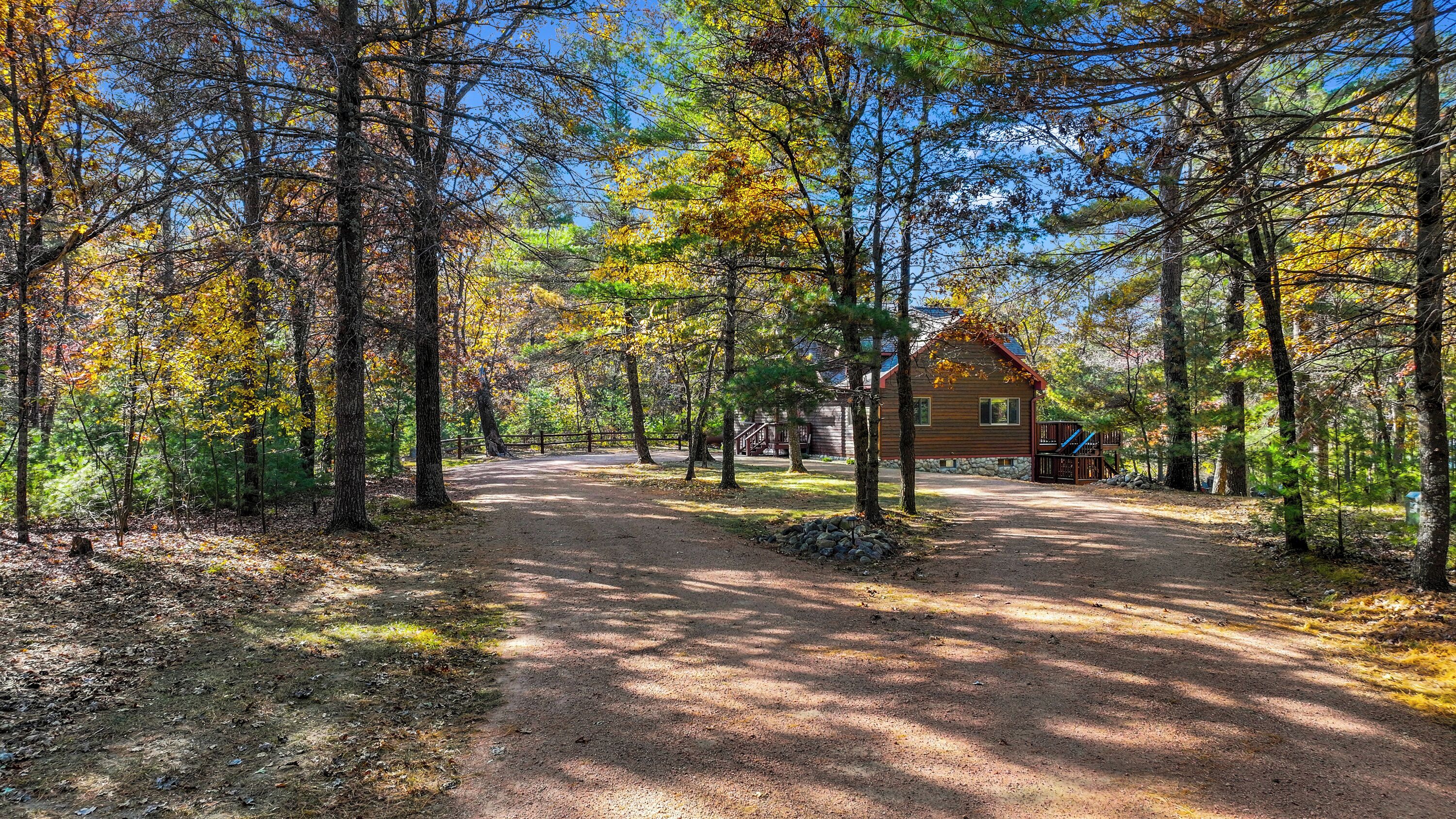 A rustic cabin surrounded by a forest with a dirt path leading to it.