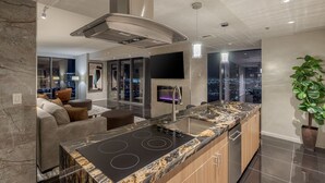 A modern kitchen with a central island, a built-in stove, and a large window overlooking a cityscape. - Remodeled Strip View 1BD/1.5BA • Balcony • Sleeps 6 • No Resort Fee • Free Parking • QJ26 (Las Vegas)
