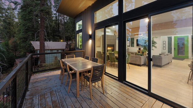 A modern house with a deck, large windows, and a visible interior with furniture. - Yosemite Park / Forest View, Patio & BBQ Area (TUOLUMNE MEADOWS)