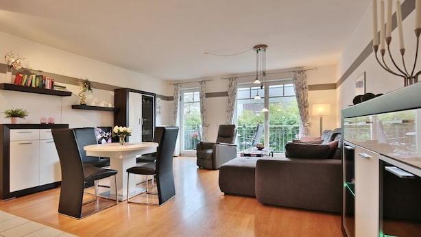 A modern living room with a dining area, a sofa, and a balcony with a view.
