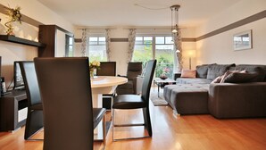 A modern living room with a dining area, a sofa, and a table with chairs.
