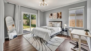Ein Schlafzimmer mit Bett, Schreibtisch, Stuhl, Spiegel und einem Fenster mit Jalousien.