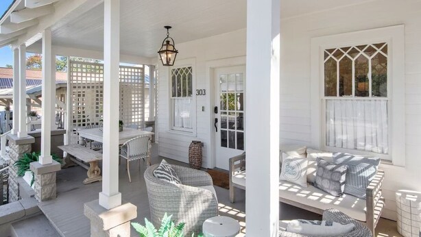 A covered patio with outdoor furniture, a white door, and a number '303' on the wall. - Historic Cottage in Olde Town BSL - One Block from Beach & Dining (Bay St. Louis)