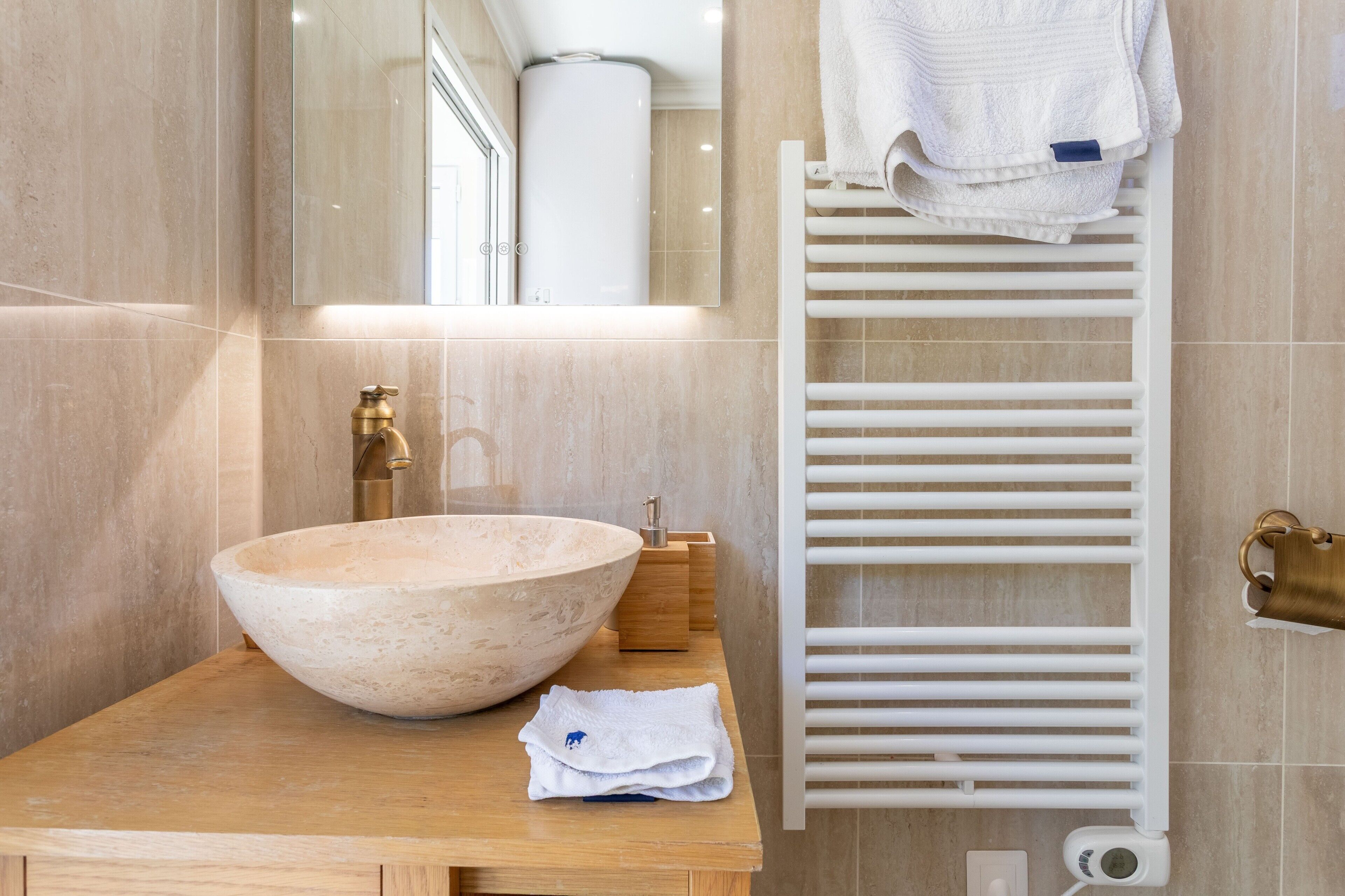Une salle de bain avec un grand lavabo en forme de cuvette, un miroir, un porte-serviettes et une serviette blanche.