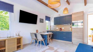 Eine moderne Küche mit blauen Schränken, einem Holzes Esstisch und einem an der Wand befestigten Fernseher.