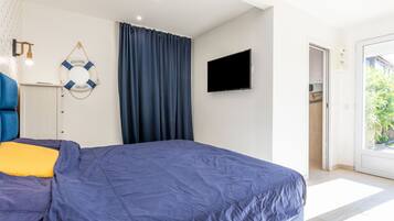 Een slaapkamer met een bed, een televisie, een decoratieve reddingsboei en uitzicht op het exterieur.