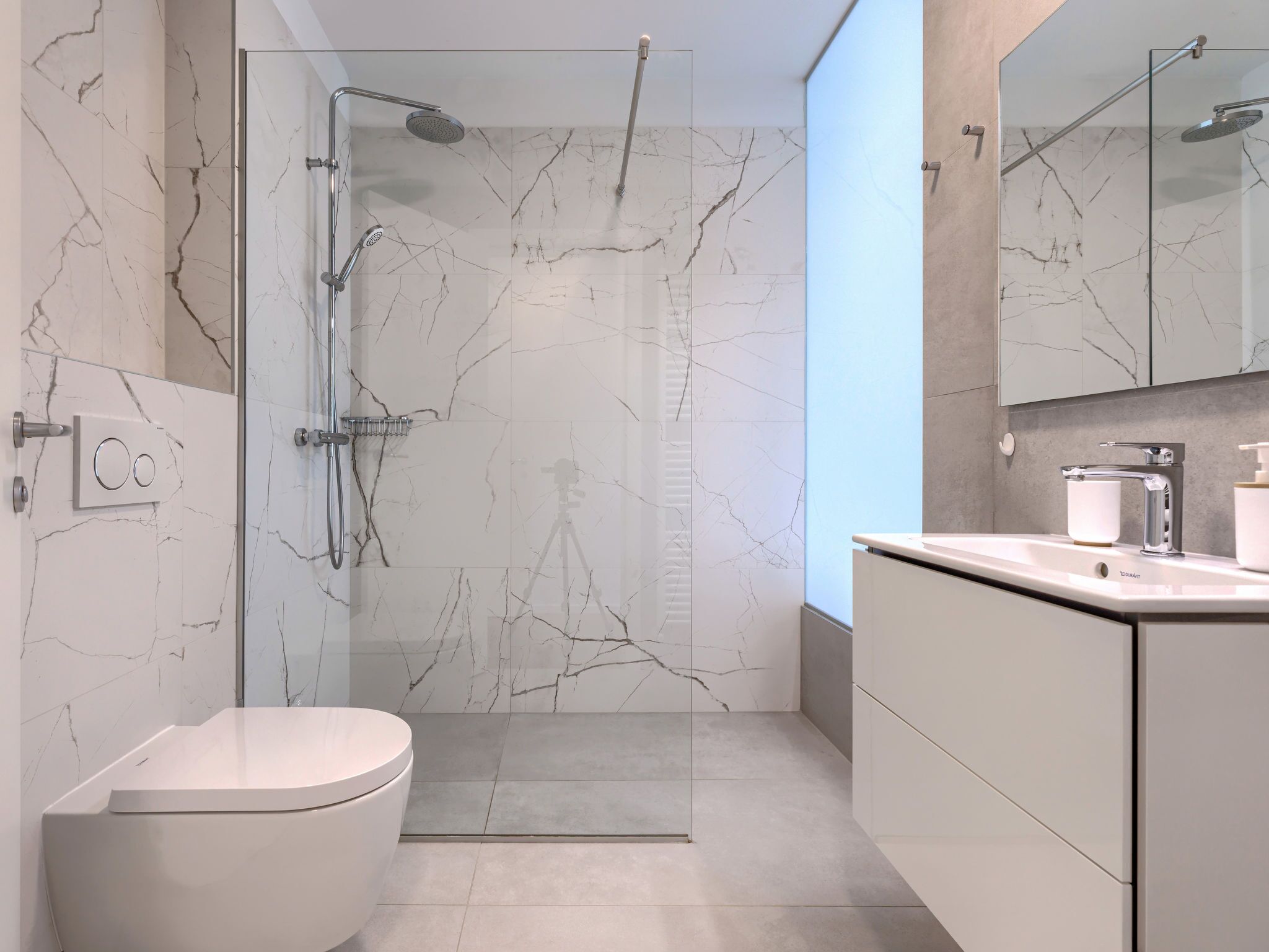 Ein modernes Badezimmer mit Glasdusche, Toilette und Waschtisch mit Spiegel.