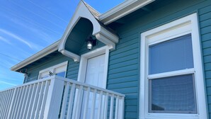 Ett hus med blå fasad, vita detaljer, en vit veranda och en garageport.