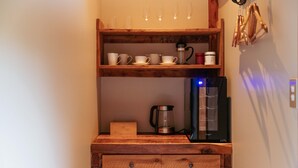 Eine Holzausstattung in der Küche mit Kaffeemaschine, Wasserkocher und Kaffeekanne. Auf der darüberliegenden Ablage befinden sich mehrere Tassen und eine Kanne.