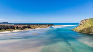 Eine Küstenlandschaft mit blauem Himmel, Sandstrand und ruhiger See.