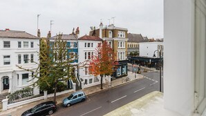 A street view with terraced houses, a parked car, and a bicycle. - Cool Notting Hill 1BR, Fully Furnished & Ready, by Blueground (London)