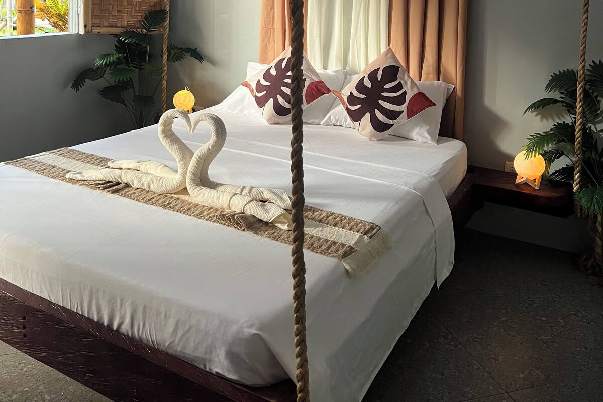 Un letto a baldacchino, con una testiera in vimini e cuscini decorativi.