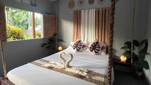 A bed with a canopy, swan-shaped pillows, and a view of greenery outside. - The Bangka Place (Enrique Villanueva)