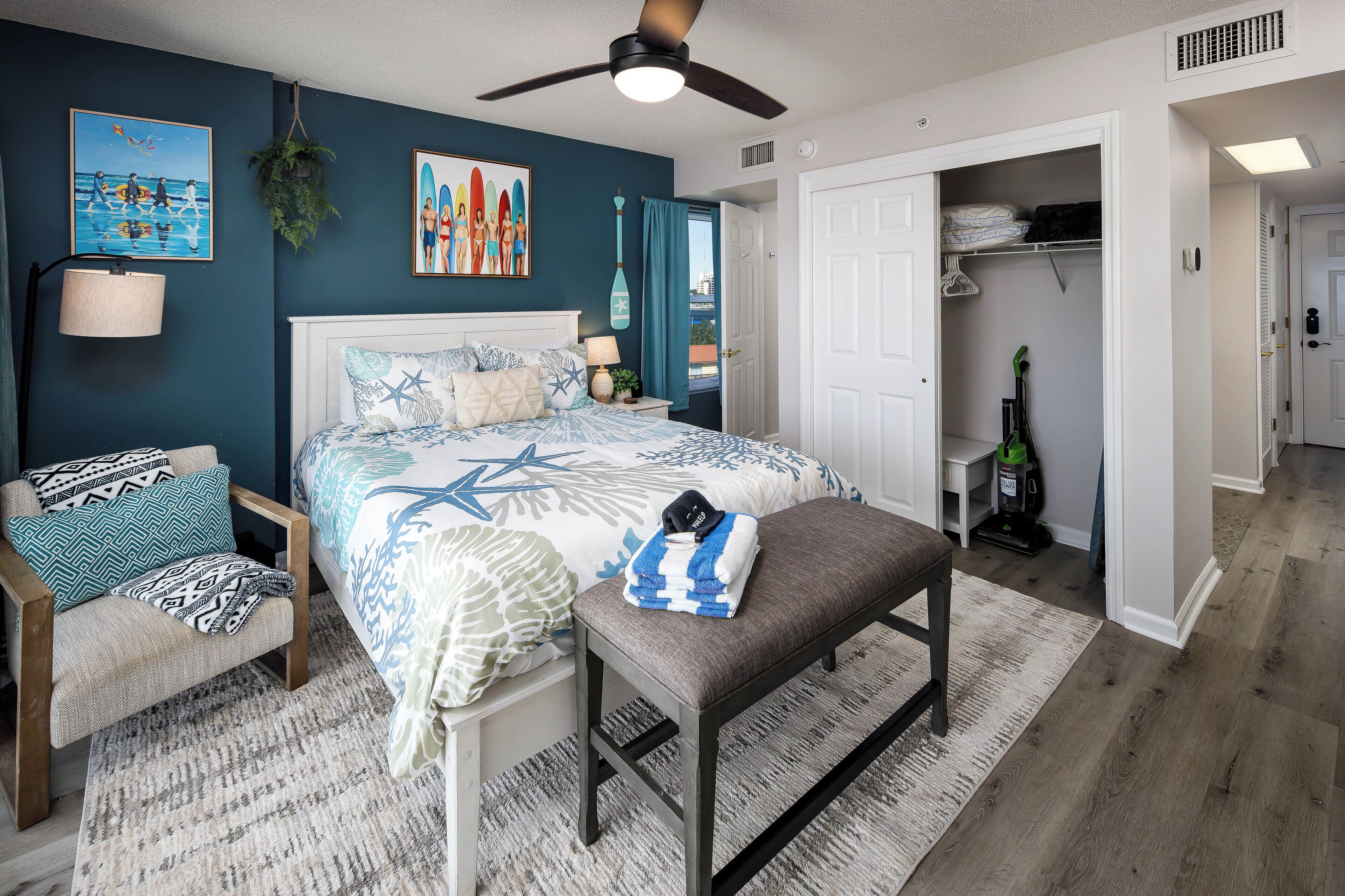 A bedroom with a bed, a bench, a chair, a bedside table, and a closet.