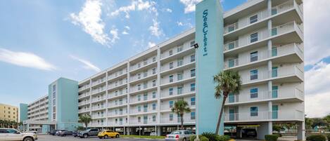 A multi-story hotel with a prominent 'SeaCrest' sign, multiple balconies, and a parking area with several cars.
