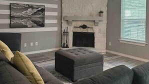 Una sala de estar con chimenea, un sofá y un cuadro grande en la pared.