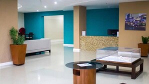 A reception area with a white sofa, a reception desk, and a glass display case. - Gated 1-bedroom Condo in Portmore with AC, WiFi, Pool, Kitchen, TV, Beach View (Portmore)