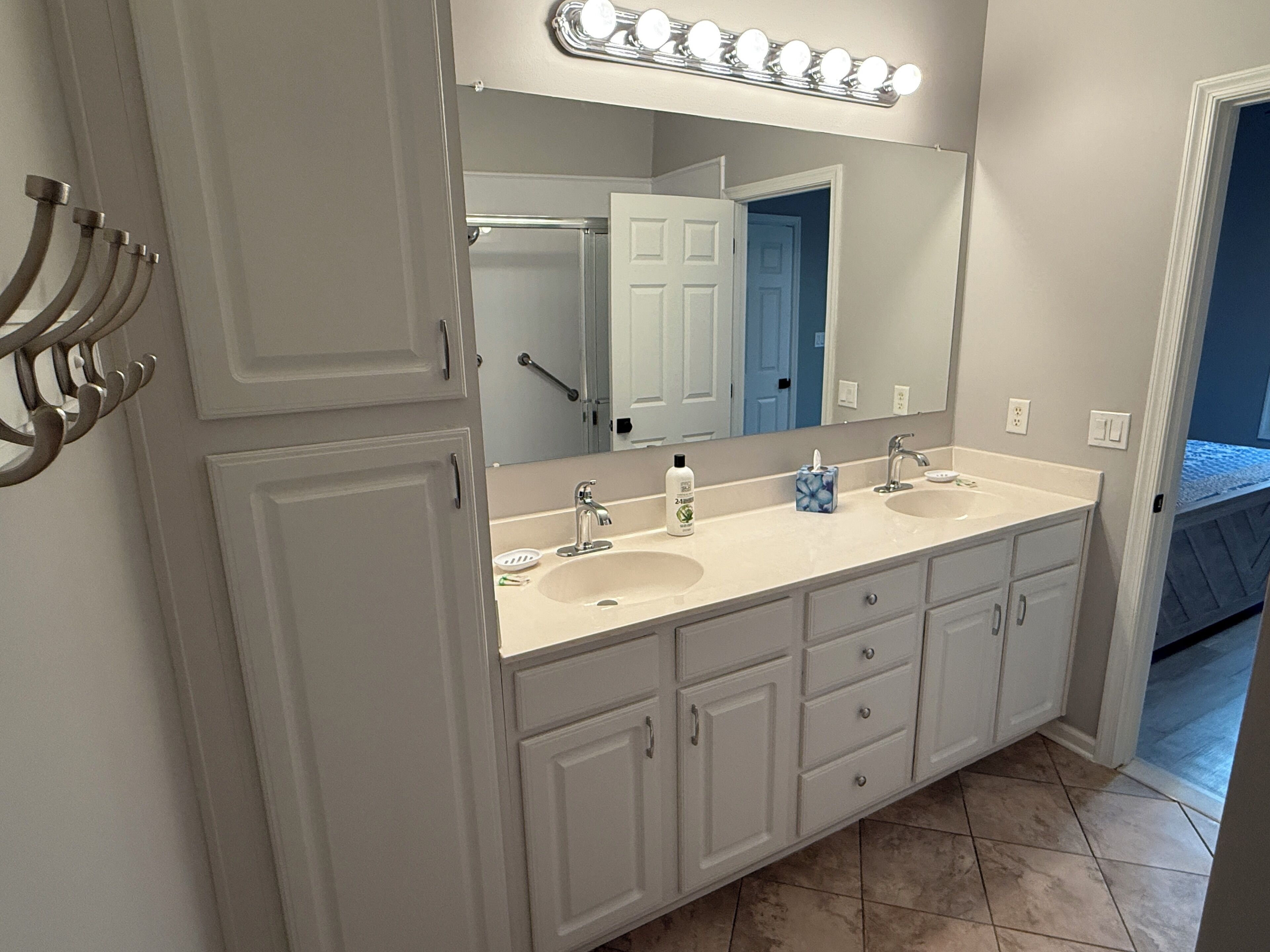 Une salle de bain avec deux lavabos, un grand miroir et un meuble-lavabo avec des tiroirs.
