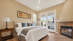 A bedroom with a bed, bedside table, lamp, and a fireplace.