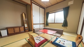 Ein traditioneller japanischer Raum mit Tatami-Böden, einem niedrigen Tisch, einer Couch und einem Holzschrank.