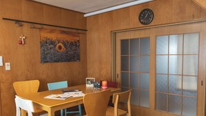 Ein Esszimmer aus Holz mit einem Tisch, Stühlen, einer Uhr und einer Schiebetür mit Milchglasfenstern.