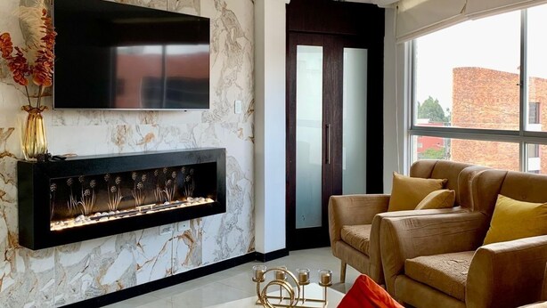 A modern living room with a fireplace, sofas, and a TV mounted on the wall. - Cozy apartment in Monteserrin! (Quito)