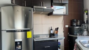 A modern kitchen with a stainless steel refrigerator, black cabinets, and a built-in stove. - Cozy apartment in Monteserrin! (Quito)