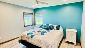 Ein Schlafzimmer mit Bett, Nachttisch und Deckenventilator.