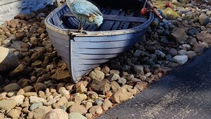 Ein Boot in felsigem Gelände nahe einem Haus.