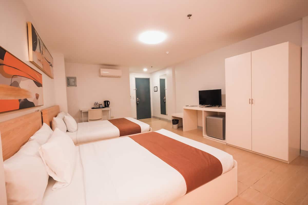 Habitación de hotel con dos camas, un escritorio, un televisor y un armario.