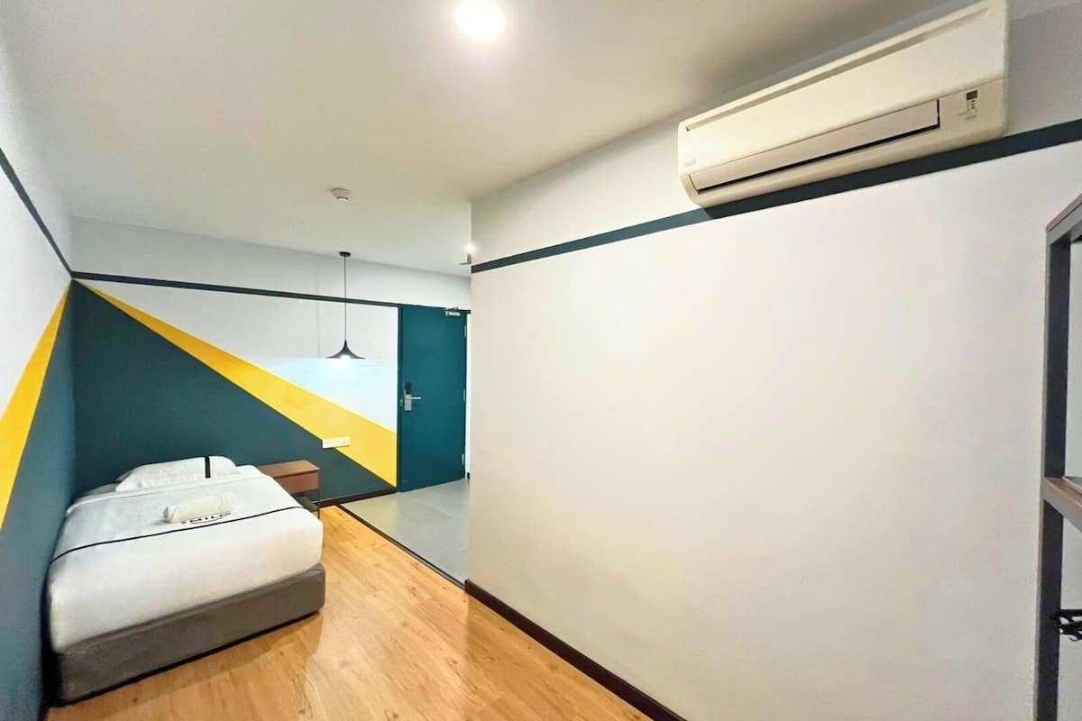 Une chambre d’hôtel moderne équipée d’un lit, d’un petit bureau et d’un appareil de climatisation.