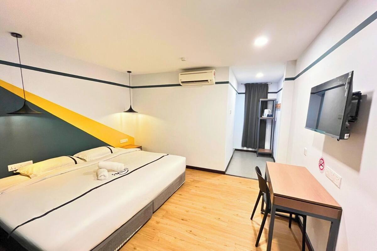 Une chambre d’hôtel équipée d’un lit, d’un bureau, d’une chaise, d’une télévision et d’un appareil de climatisation.