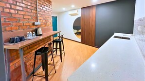 Eine moderne Küche mit Backsteinwand, Holzbalken und Barhocker.