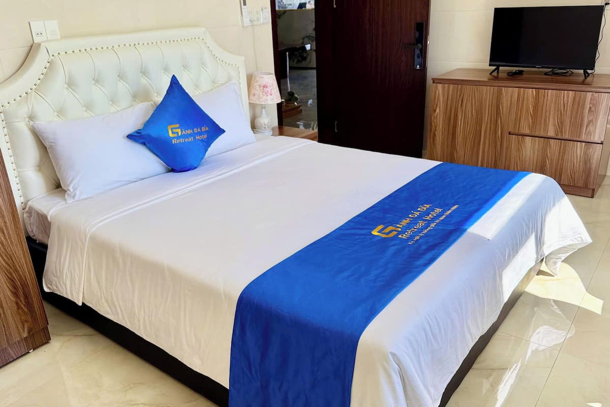 A hotel room with a bed, a television, and a wooden cabinet.