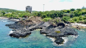 Enjoy breathtaking ocean views from this natural viewpoint, overlooking a lush landscape and a modern hotel in the distance.