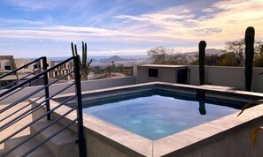 Una piscina en la azotea con una vista despejada del paisaje circundante, incluyendo cactus y montañas distantes.