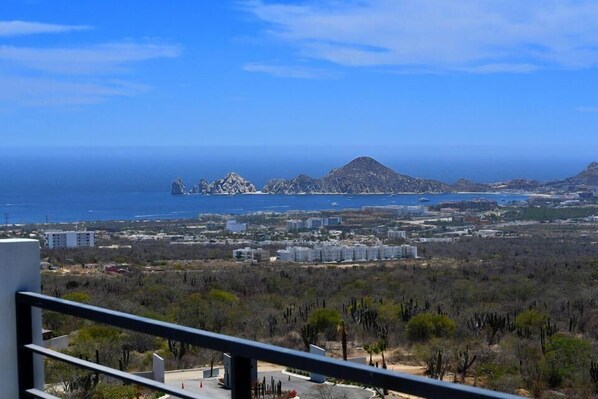 Un paisaje costero con edificios, una playa y una cadena montañosa.