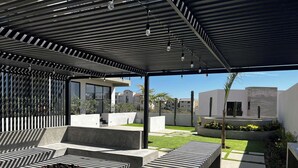 Un patio moderno al aire libre con asientos geométricos y vistas de edificios circundantes.