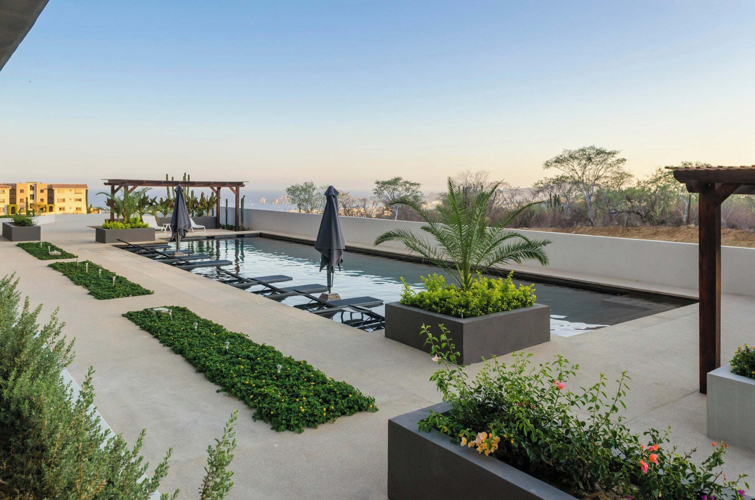 Una piscina al aire libre, sombrillas, sillones reclinables de piscina