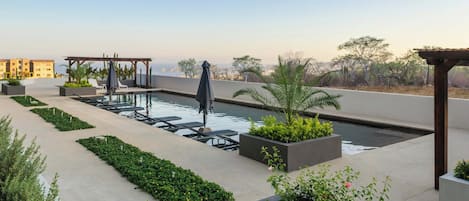 Alberca al aire libre, sombrillas en la alberca y camastros