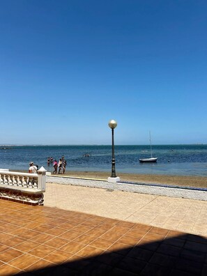 Uma praia com um calçadão de azulejos, um poste de luz e vista clara do mar.