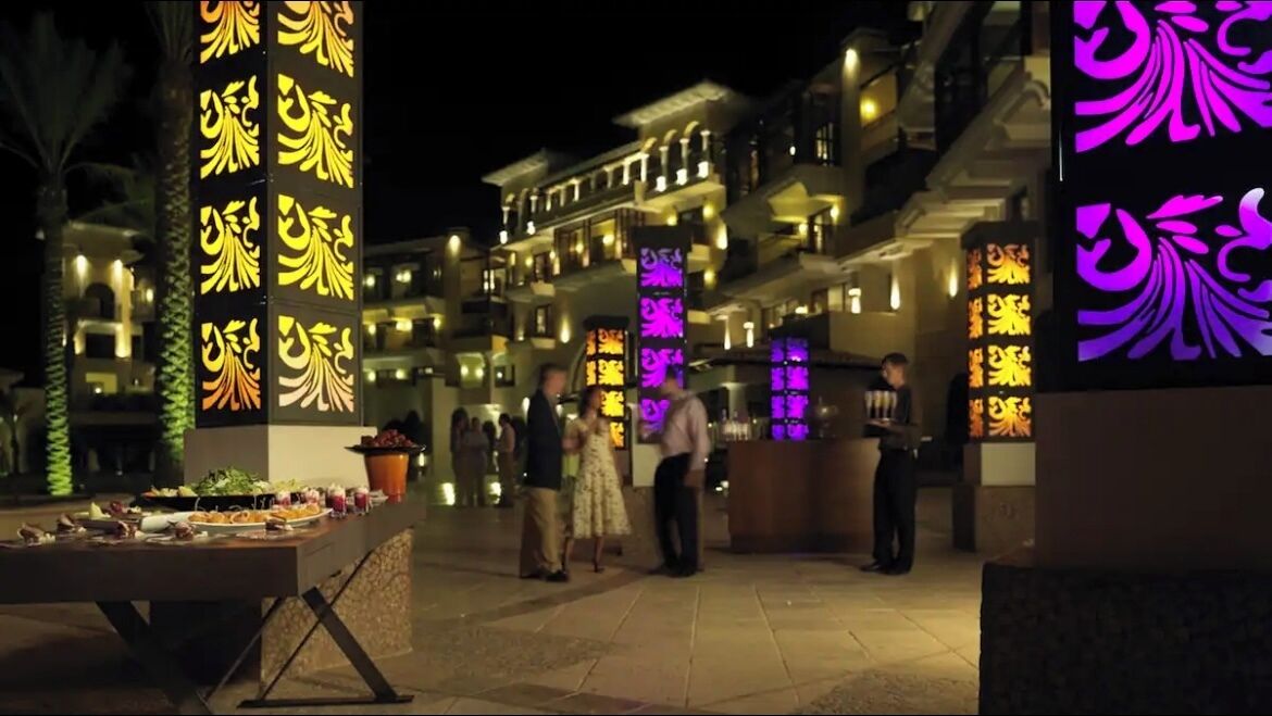 Un hall d’hôtel comprenant un comptoir d’accueil, une table de buffet et des piliers décoratifs ornés de motifs illuminés.