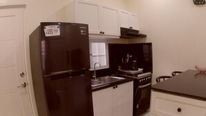 A compact kitchen with a black refrigerator, white cabinets, a stove, and a sink. - Entire home/Fully furnished/Netflix/AC/Wash/Dyer (Daet)