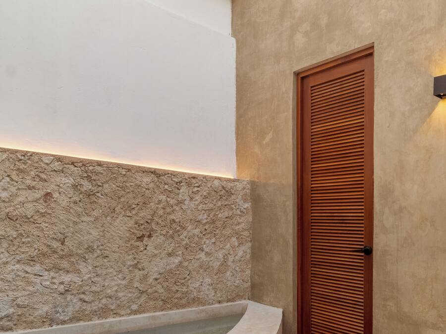 Un espace spa agrémenté d’un mur en pierre, d’une porte en bois et d’un jacuzzi encastré.
