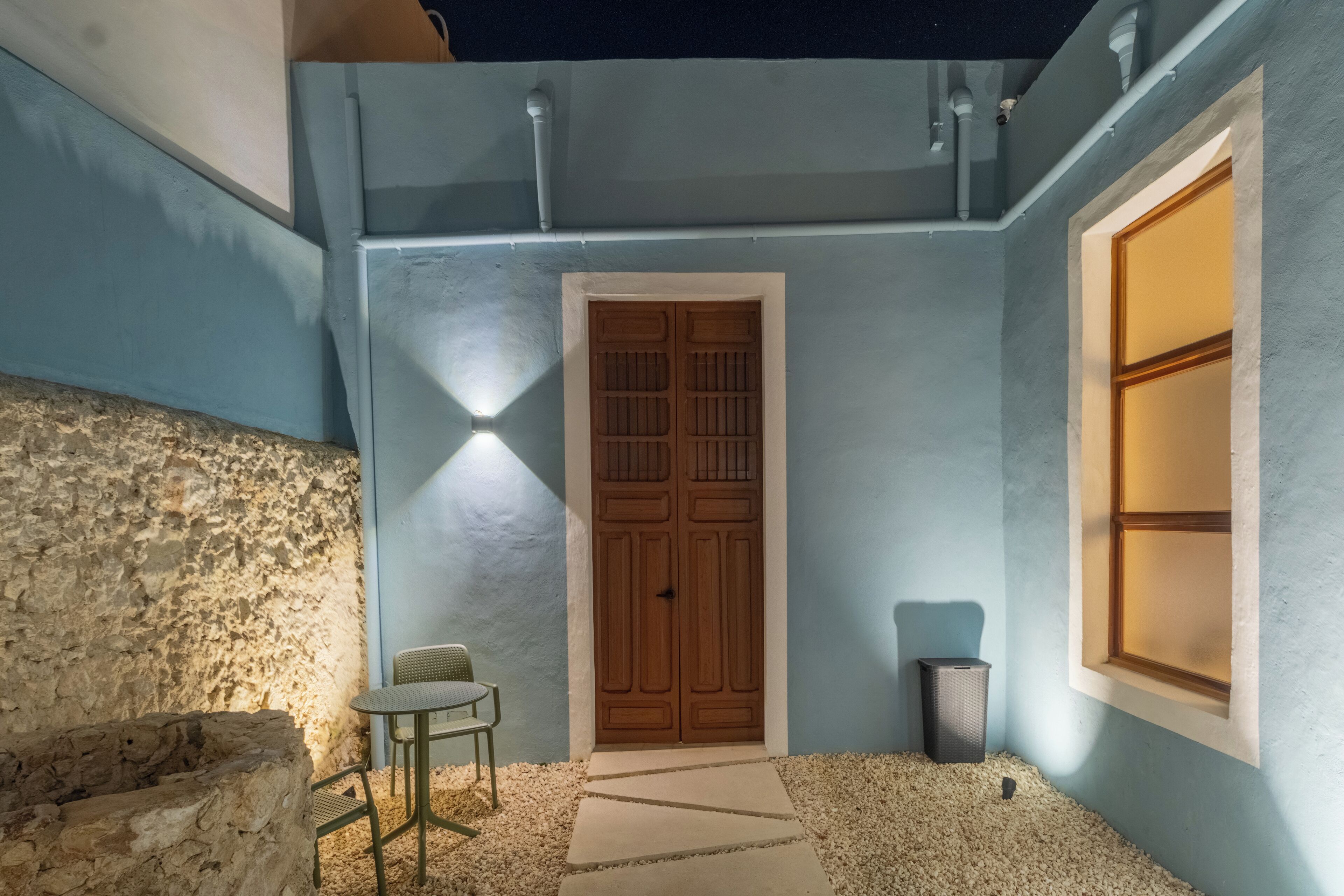 Façana d'edifici amb una porta de fusta, una finestra i un mur de pedra.