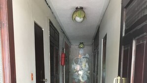 Un pasillo con puertas a ambos lados, suelo de baldosas y una lámpara en el techo.