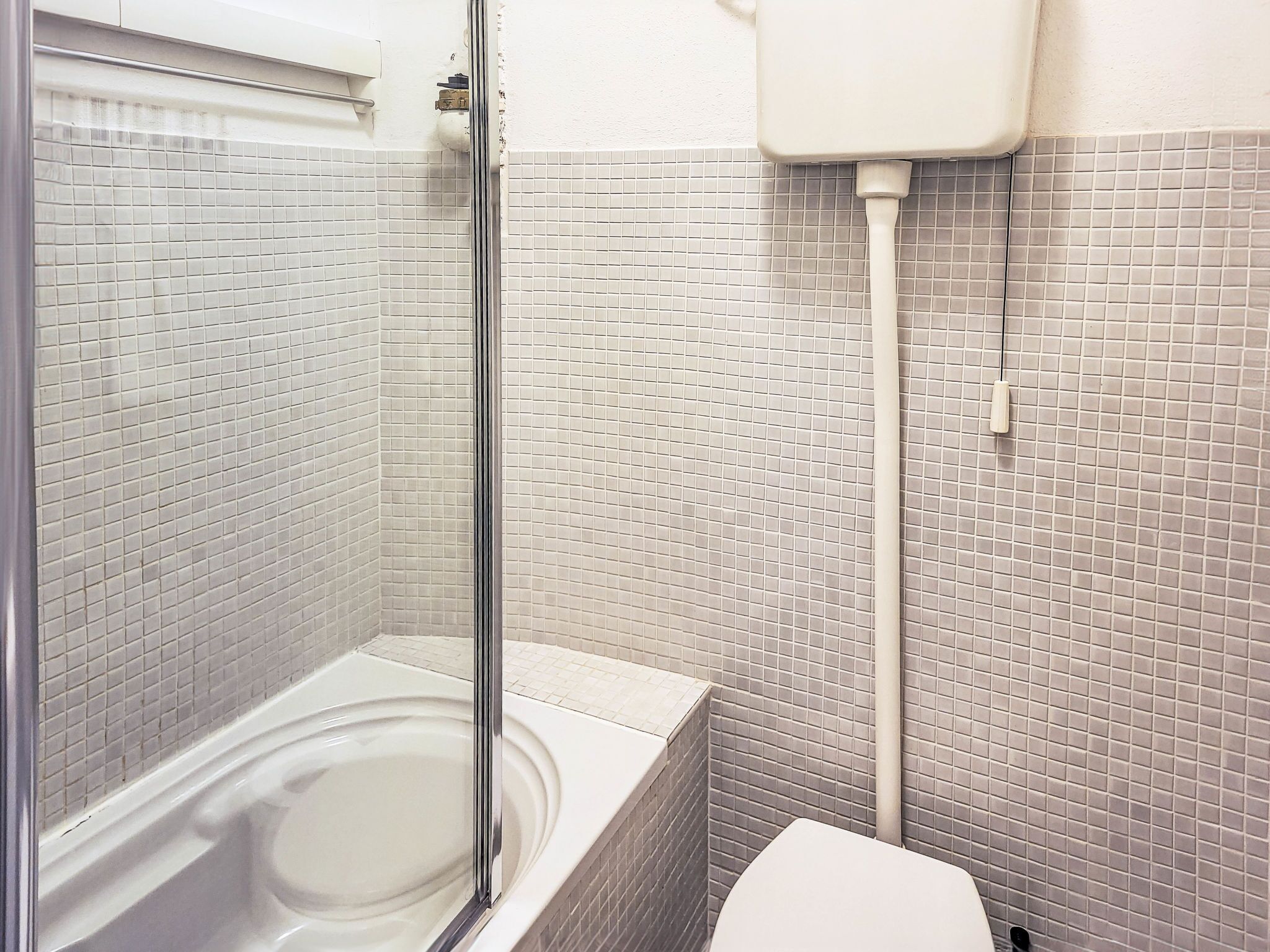 A bathroom with a glass shower enclosure, a bathtub, and a toilet.