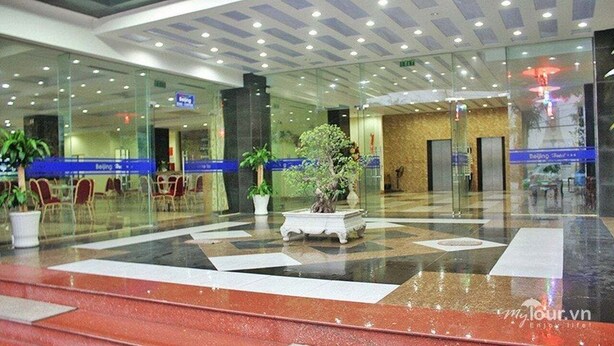 A lobby with glass walls, seating areas, and potted plants. - Bac Kinh Hotel Vinh - by BAY LUXURY (Vinh Phu)