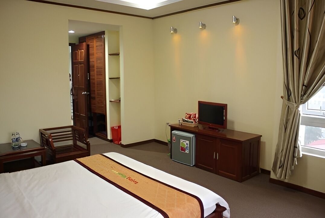 Une chambre d’hôtel équipée d’un lit, d’un bureau, d’une télévision et d’une armoire.