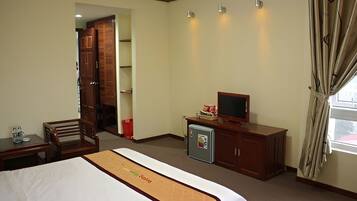 Une chambre d’hôtel équipée d’un lit, d’un bureau, d’une télévision et d’une armoire.
